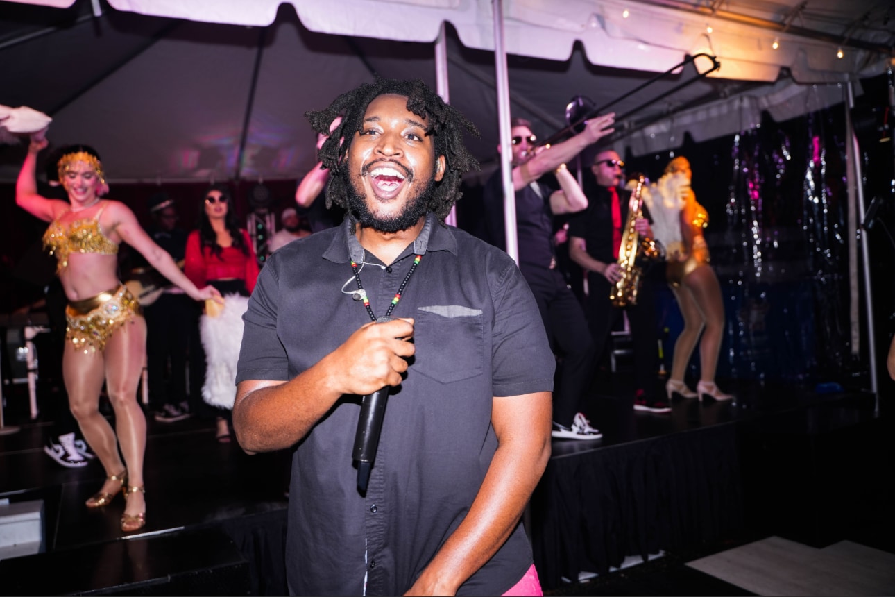 Gee Scott singing with performers onstage.